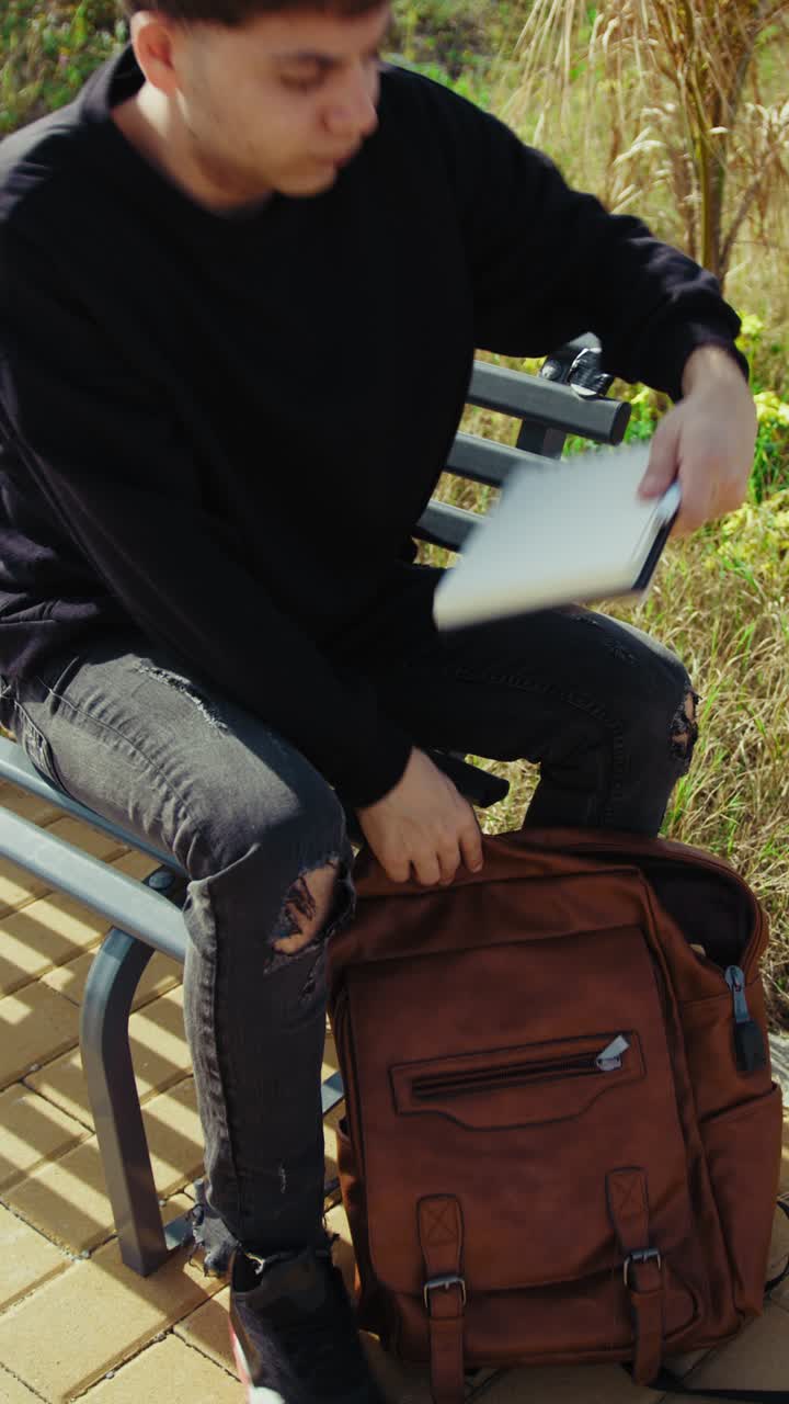 Man Sitting On A Bench In The Nature Searching For Something In The Backpack