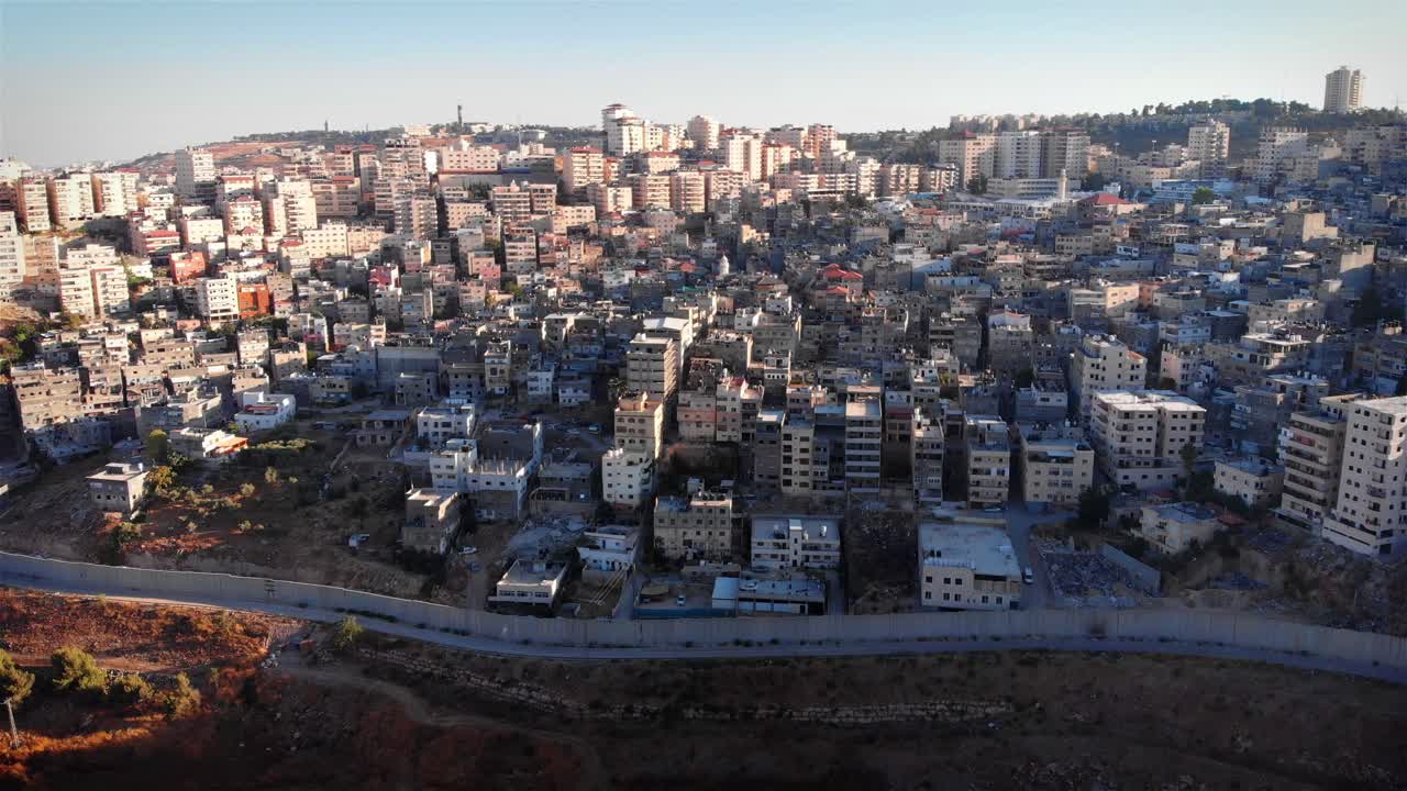 Aerial view of a densely populated city with a separation wall