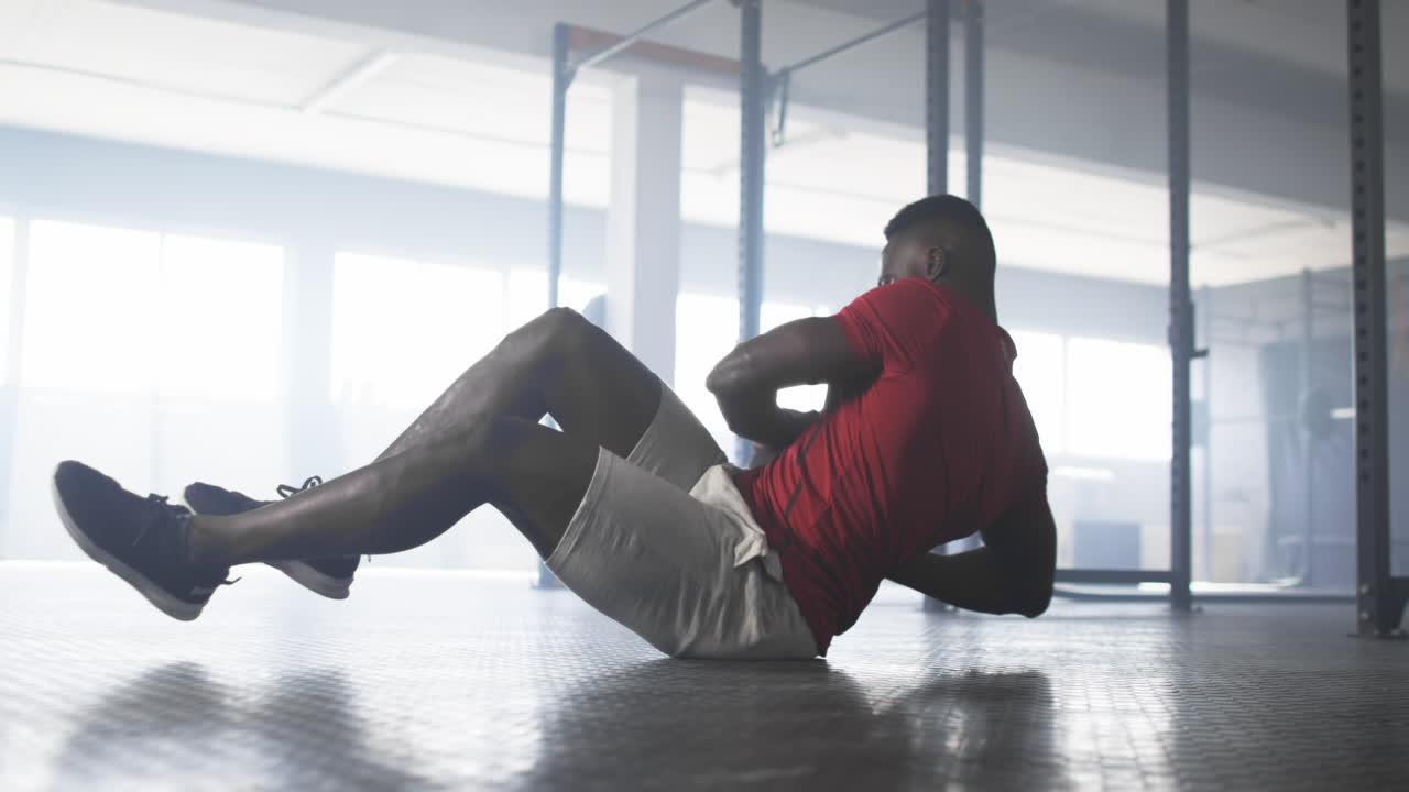 Exercising in gym, man in red shirt doing floor workout routine