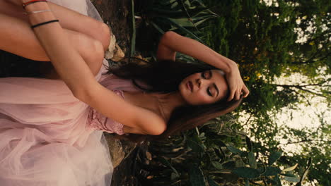 Close-up-shot-of-a-pretty-young-woman-wearing-pink-gown-and-posing-with-green-vegetation-in-the-background