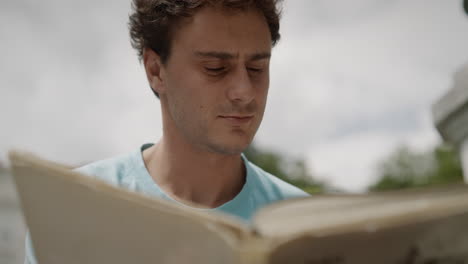 jovem sentado no parque tivoli e lendo um livro, o sol está brilhando sobre ele em um dia de verão