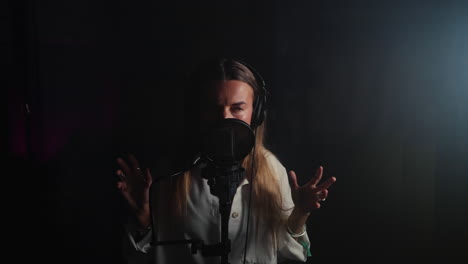 woman singing into microphone in recording studio