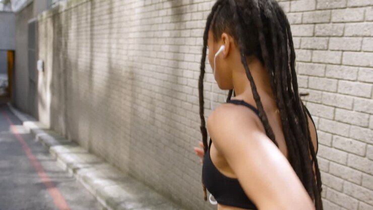 Vista posteriore di donna afroamericana che fa jogging in città 4k