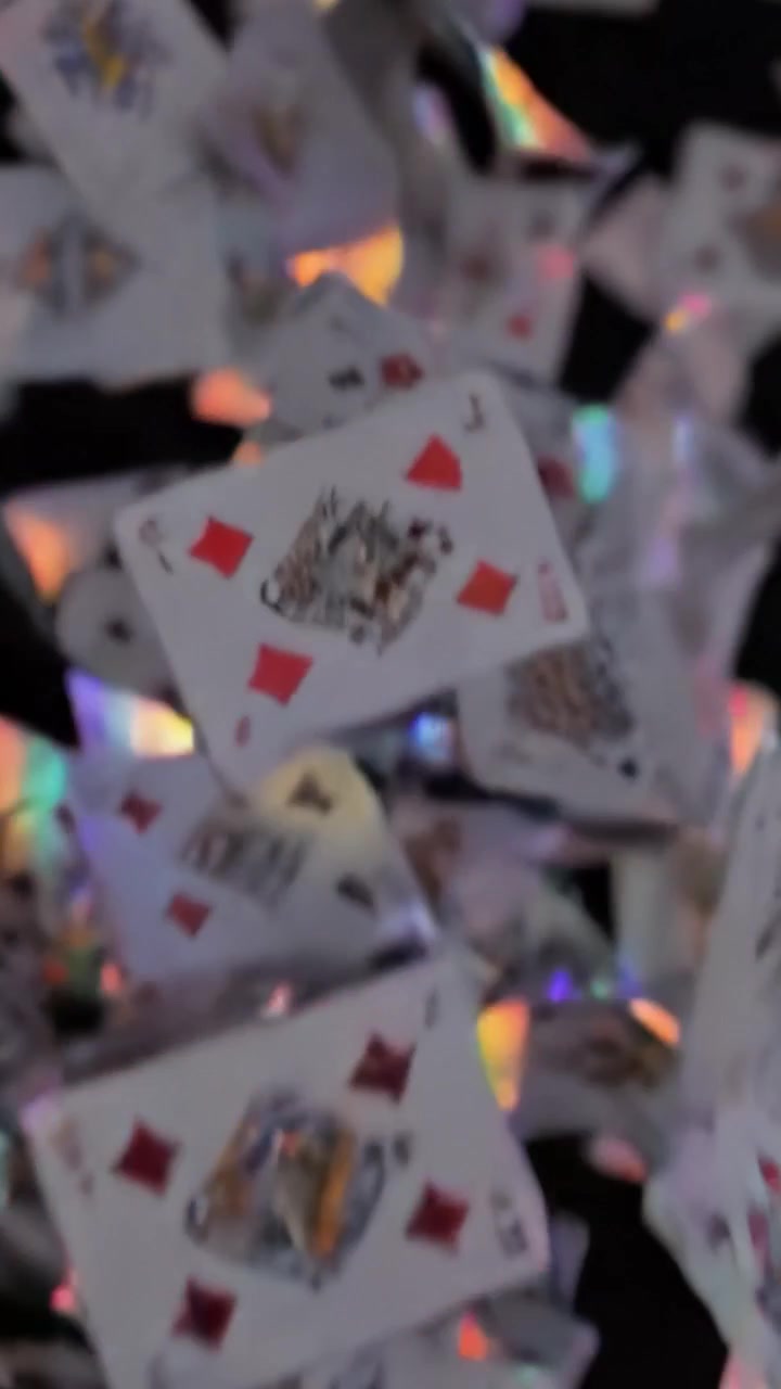Uno spettacolo ipnotizzante di carte da gioco a mezz'aria che crea un'esperienza visiva incantevole di movimento e colore su uno sfondo scuro.