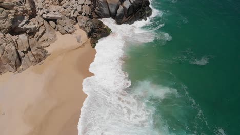 Luftaufnahme-Von-Wellen,-Die-Neben-Einer-Felsformation-Auf-Den-Strand-Krachen