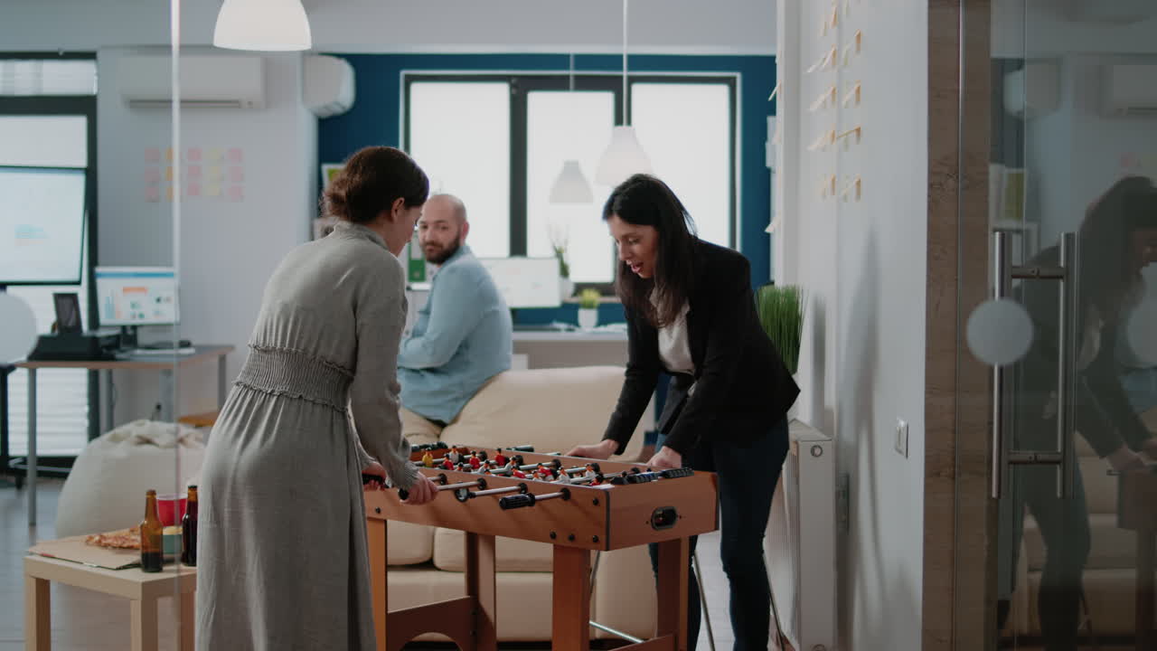 Women playing with foosball game table to have fun after work