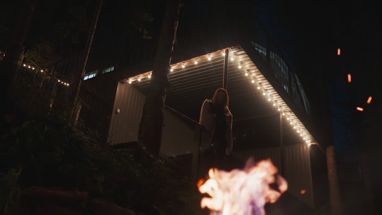 la esposa baja las escaleras hacia la hoguera. la joven opta por momentos solitarios en el terreno del campamento creando un ambiente propicio para la contemplación a última hora de la noche.