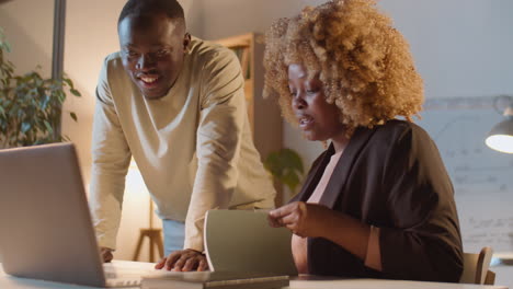 african american colleagues working together in office at night