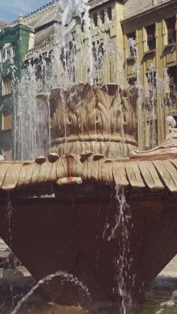 Vista ravvicinata al rallentatore dell'acqua che scorre a cascata dalla Fontana dei Pesci in Piazza della Vittoria, catturando un rinfrescante punto di riferimento urbano a Timisoara