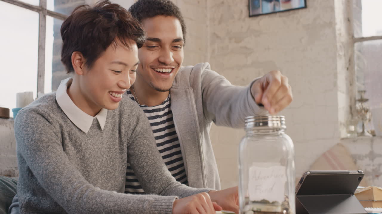 Happy mixed race couple saving money in adventure fund jar
