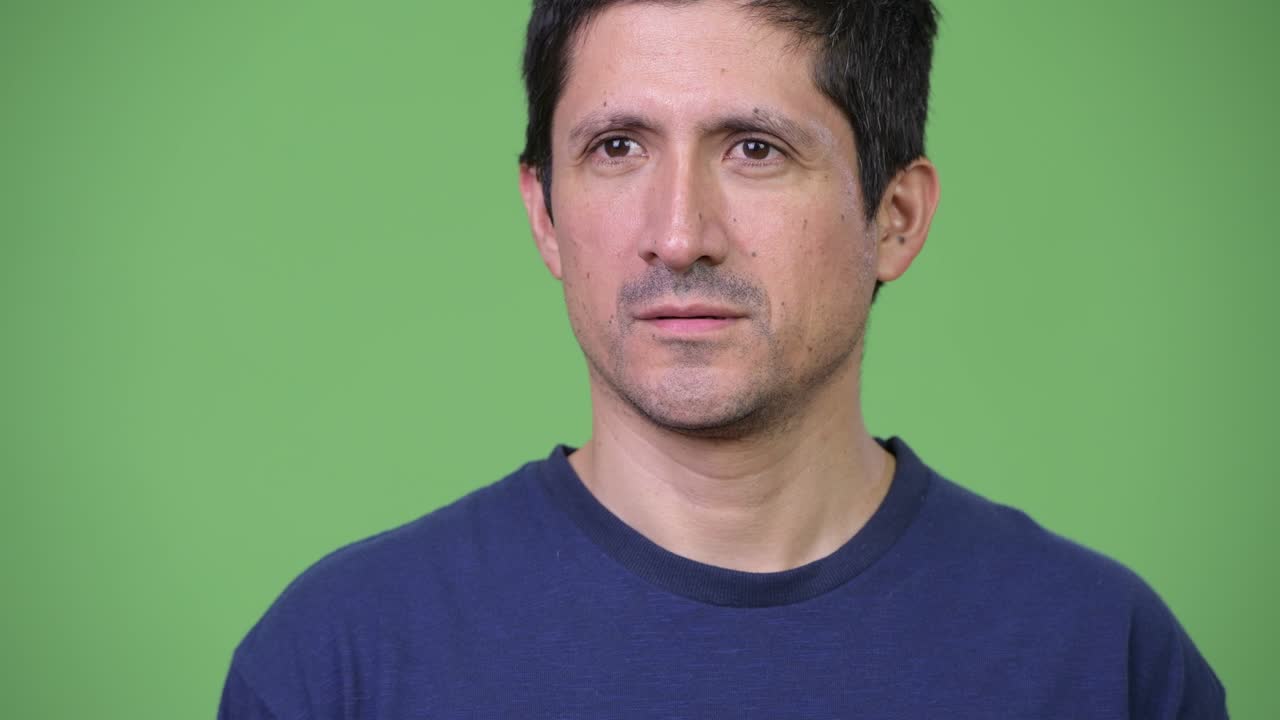 Uomo ispanico pensieroso su sfondo verde