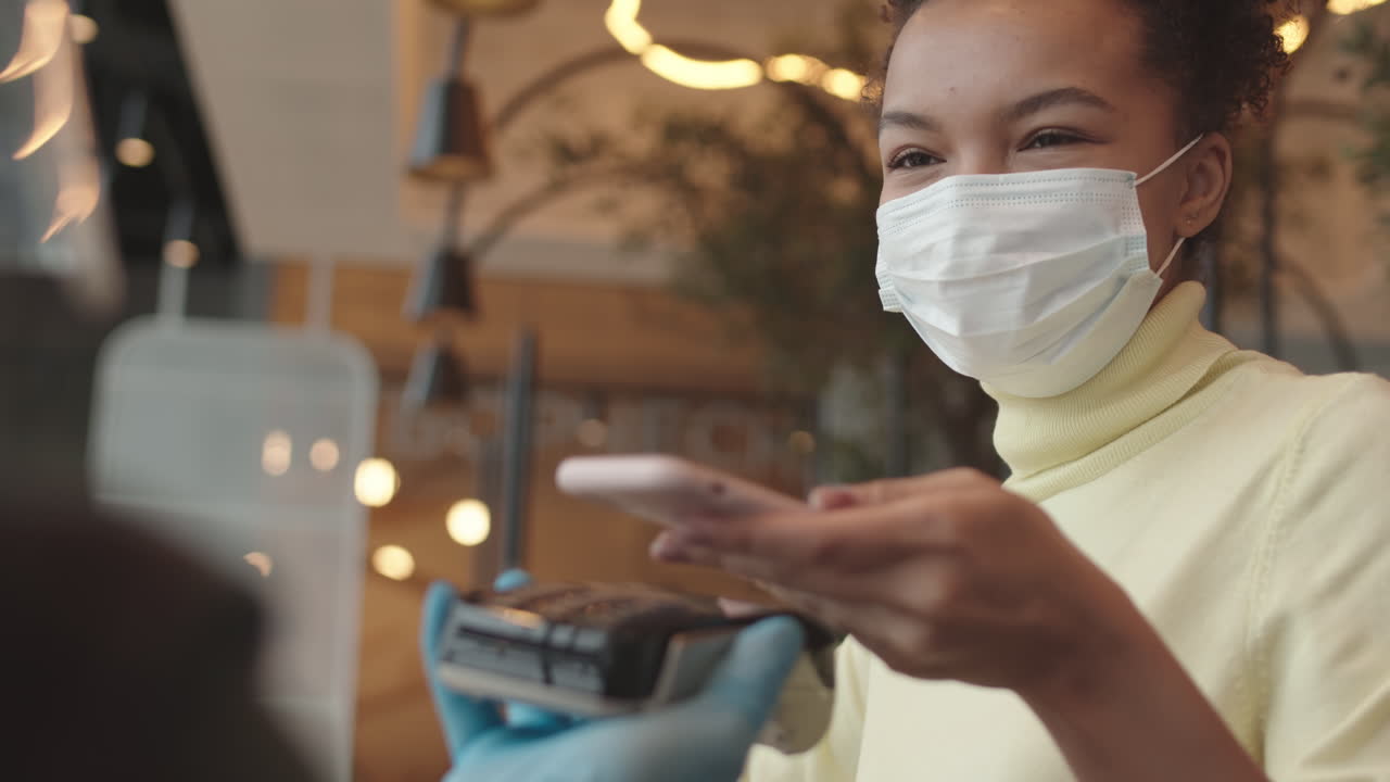 Woman in Mask Paying with Smartphone