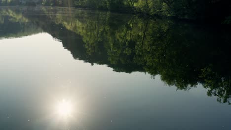 calm river on sunny summer morning with sun reflection on water surface, dordogne river