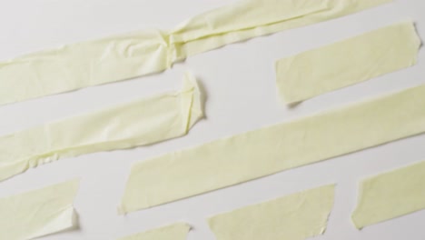 video of close up of multiple torn piece of yellow paper with copy space on white background