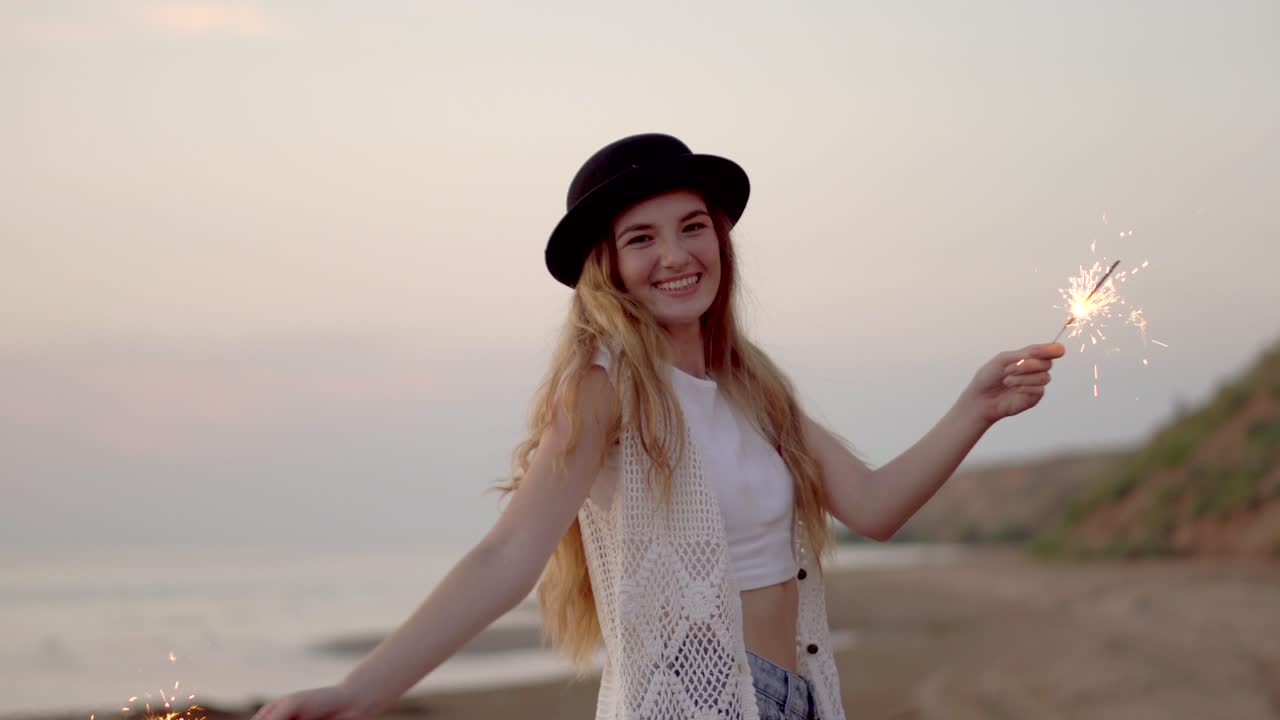 Happy Woman with Sparkler on the Beach at Sunset