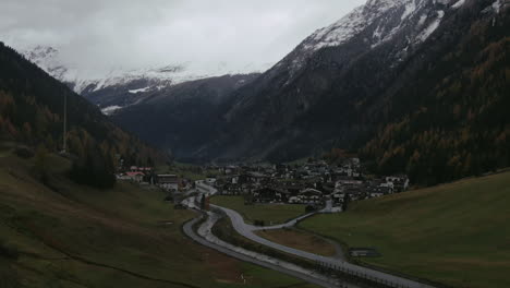 vuelo aéreo hacia adelante sobre un valle montañoso con un pequeño pueblo en el fondo - austria, kauntertal