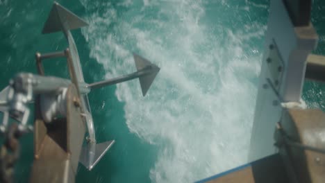 Mid-shot-of-rear-end-of-boat-cruising-across-the-ocean-with-anchor-in-foreground