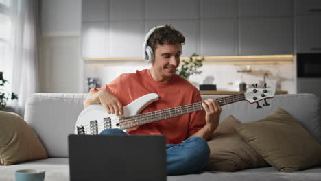 happy musician playing guitar living room. smiling man recording music tutorial