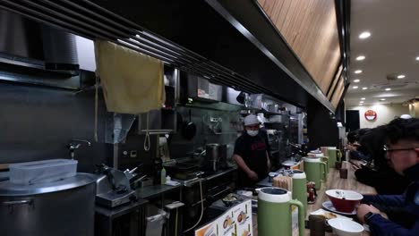 chefs preparing ramen in a bustling kitchen