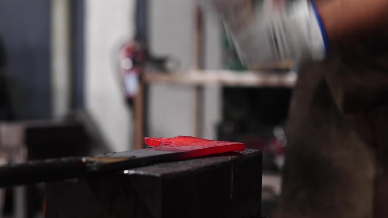 herreros forjando metal caliente con martillo en el taller