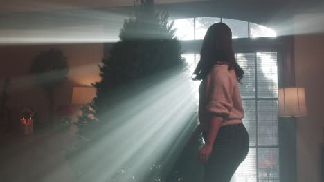woman with christmas tree in sunlit room
