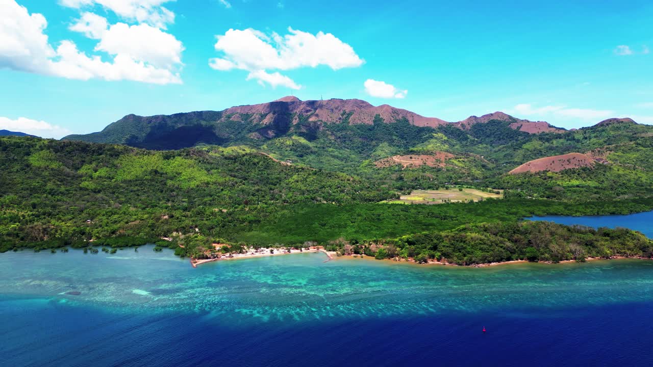 Aerial view of a tropical island bay with mountains and clear blue water