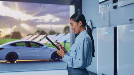 side view of asian female with her tablet with home energy storage system in a modern garage, checking on her tablet with meditation
