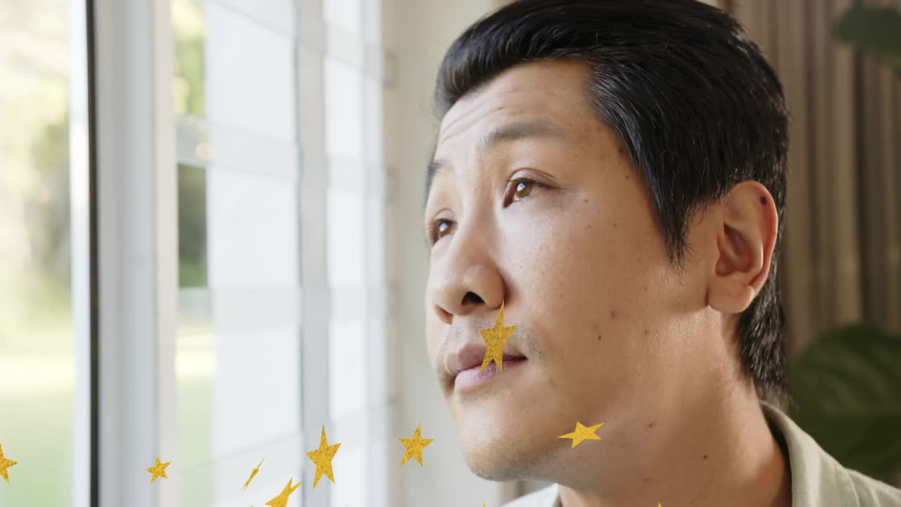 Man sitting by shuttered window, watching drifting gold stars causing gaze, smiling for marketing