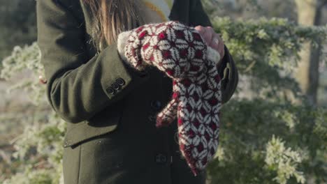 mujer vistiendo mitones estampados de punto rojo en el frío y soleado día de navidad
