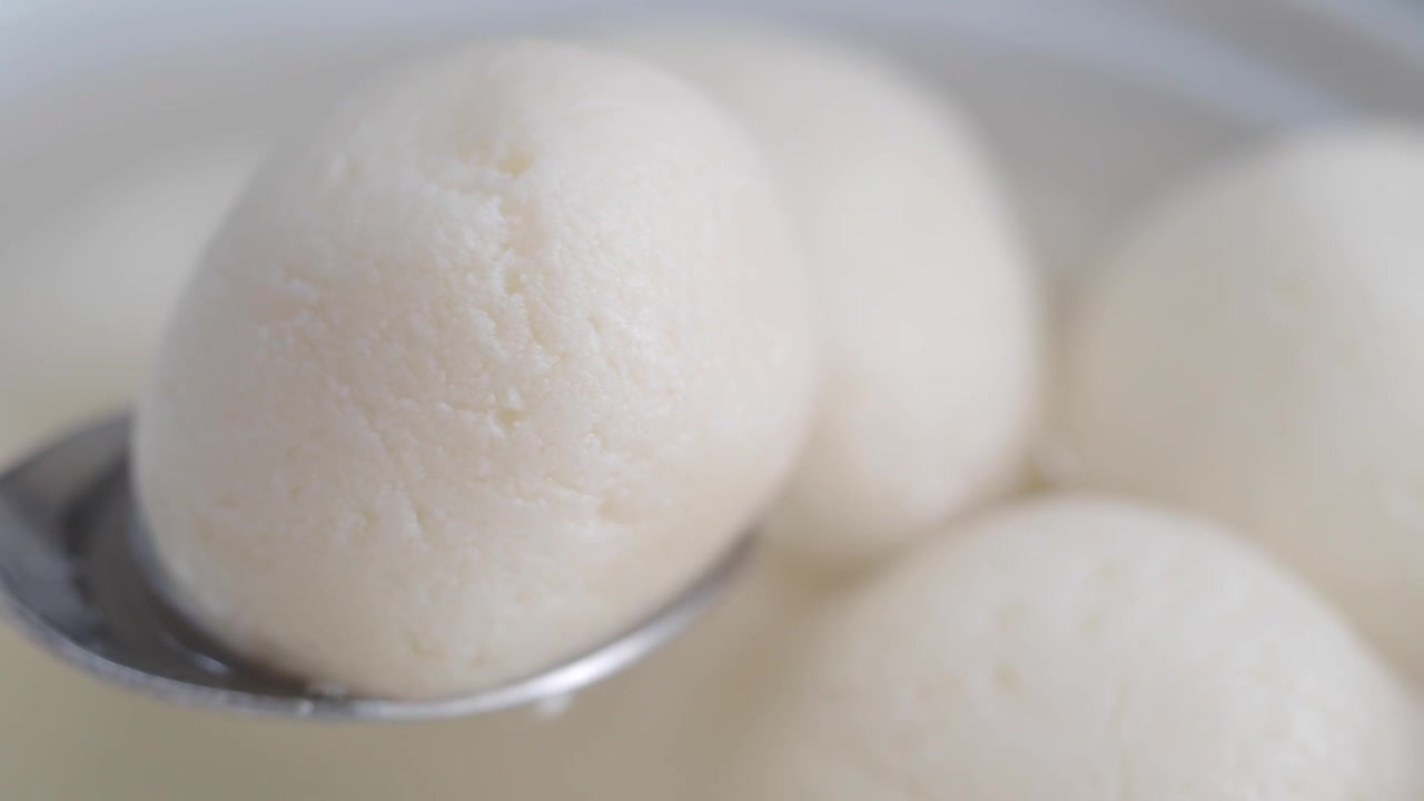 Spoon Lifting a Rasgulla from a Bowl of Syrup