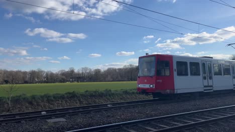 Tram-drives-into-the-picture-over-a-railway-line-in-good-weather-and-past-the-camera