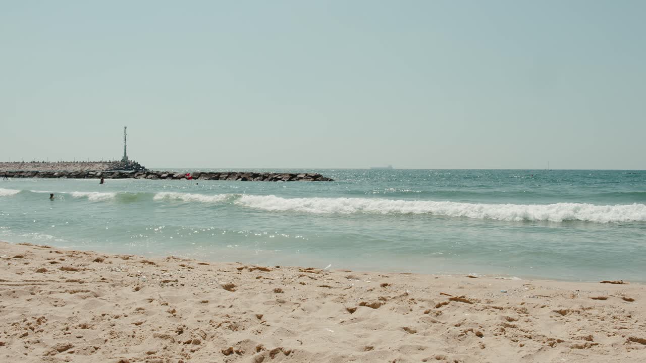 파도가 먼 방파제에 부딪힐 때 이스라엘의 푸른 지중해 해안 기슭의 긴 팬 샷