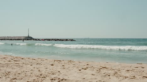 toma panorámica larga de las costas de la costa mediterránea azul de israel cuando las olas golpean el rompeolas distante