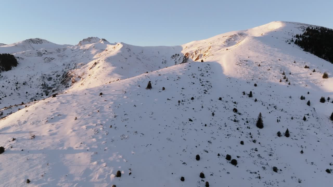 aerial vieaw of Snowy mountains under soft sunlight, tranquil winter scene.