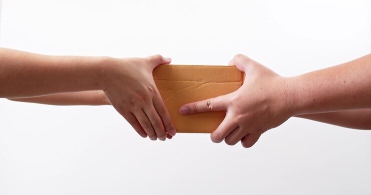 Close up of Woman's hand receiving a parcel cardboard box from a delivery man who gives her a postal package box isolated on a white studio background. Shipping and Delivery concept.
