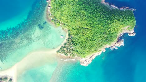 Tropical-island-with-lush-vegetation-and-rocky-coastline-isolated-in-the-middle-of-blue-turquoise-sea-water-in-Ko-ma,-Phangan,-Thailand