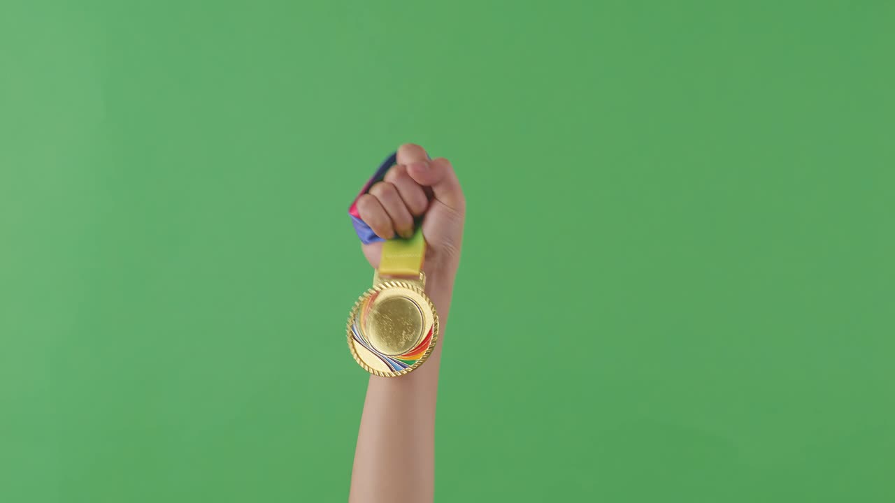 手に持った金メダル。グリーンバックの背景。