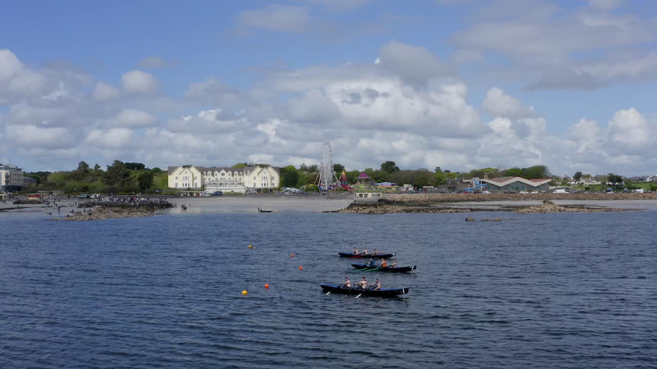 Static drone shot of currach boats tethered tied down to buoys, galway ireland coast behind