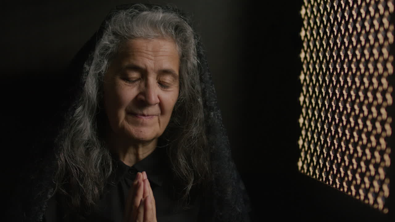 Senior Woman in Mantilla Making Confession with Hands in Prayer