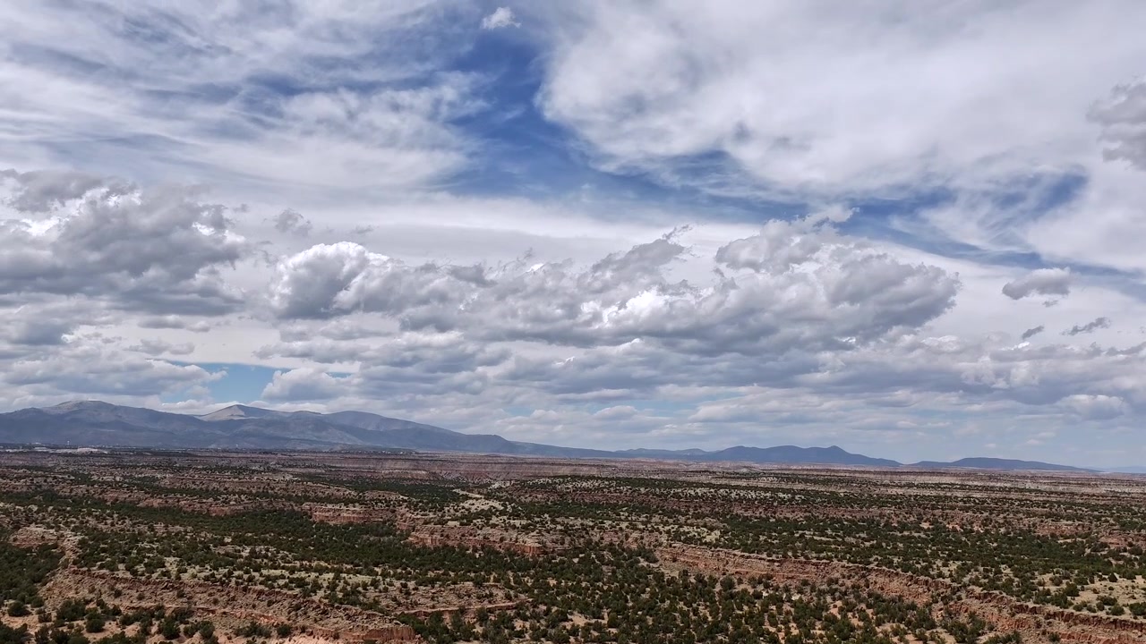 En svævende filmisk timelapse afslører et majestætisk, vidtstrakt landskab af ørkenplateauer. Dynamiske rullende skyer udvikler sig smukt hen over den sydvestlige himmel og bevæger sig hurtigt over den barske vildmark.