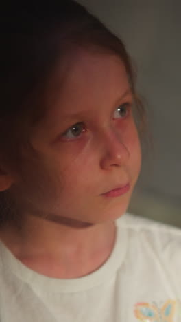 crying child abuses victim in semi-dark room closeup. little girl with water eyes of offence on blurry background. scared kid suffering from violence