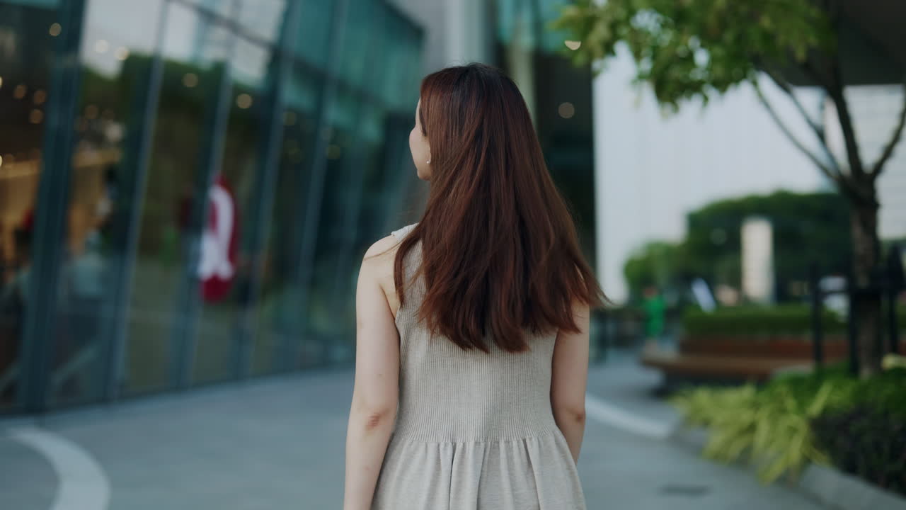 หญิงสาวเดินออกไปในสภาพแวดล้อมเมืองที่ทันสมัย