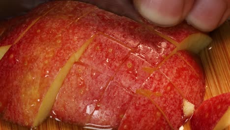 very sharp knife chopping slices of a red, fresh apple