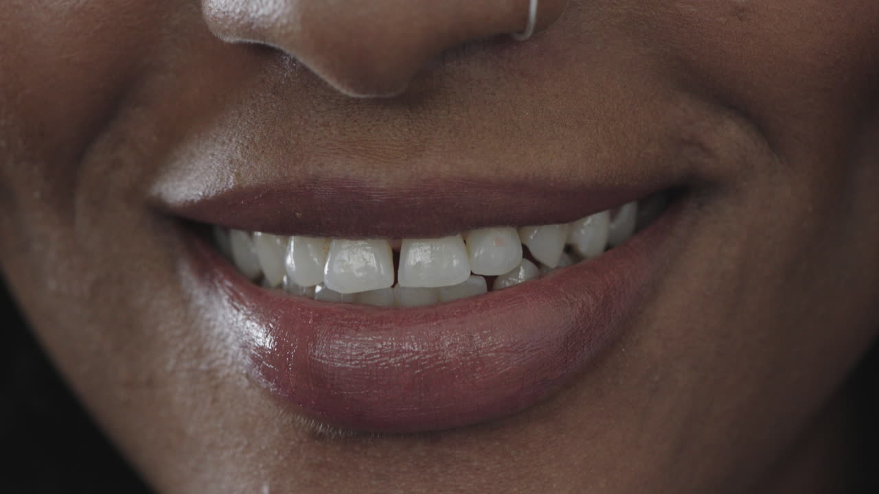 primer plano de una mujer afroamericana labios brillantes sonriendo feliz mostrando dientes sanos hermosa piel perfecta
