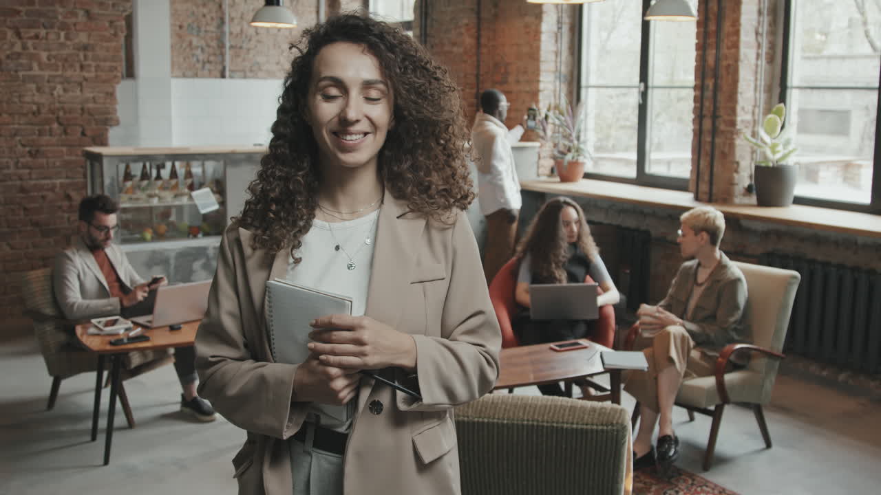 Young Businesswoman Posing for Camera with Notebook in Hands