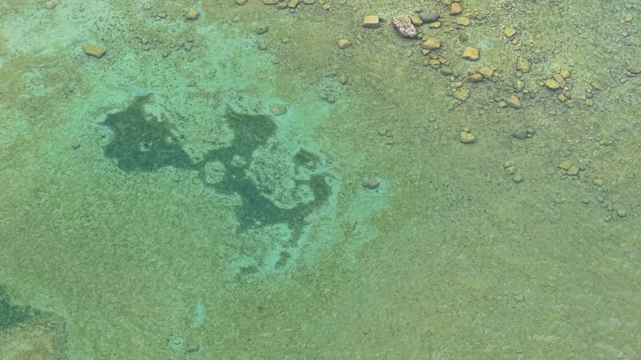Aerial drone view of shallow turquoise waters with rocks visible beneath the surface near the Les Cheneaux Islands in Michigan’s Upper Peninsula