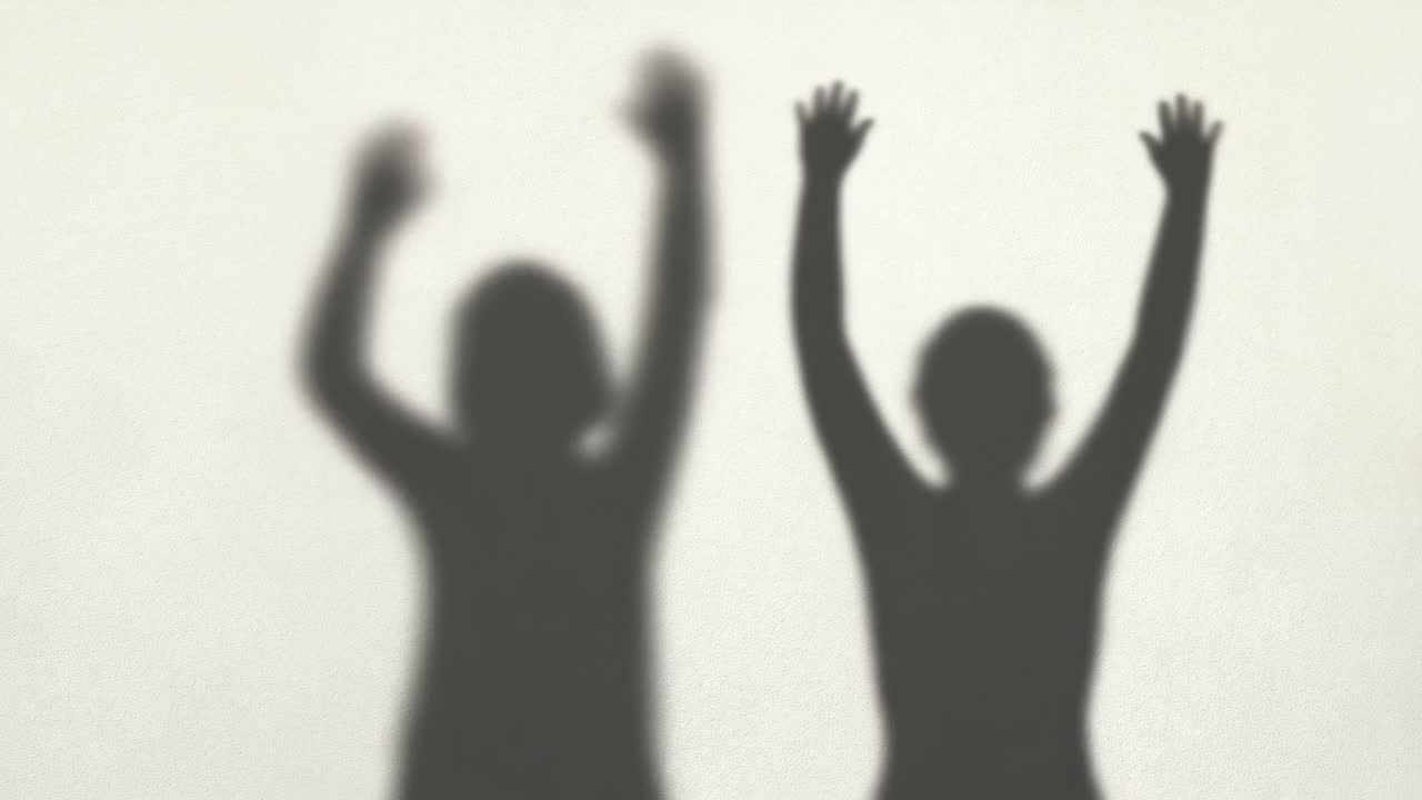 Blurred Silhouettes of Two People Raising Arms in Celebration