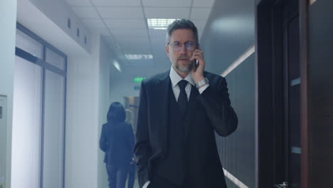 un hombre de negocios hablando por teléfono en el pasillo de la oficina.