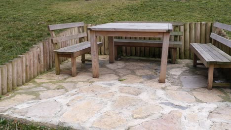 mesa de patio de madera y bancos en un jardín