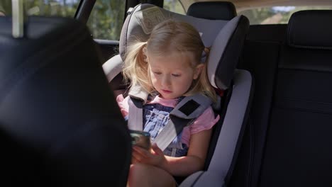 video de una niña en el asiento trasero de un coche con teléfono